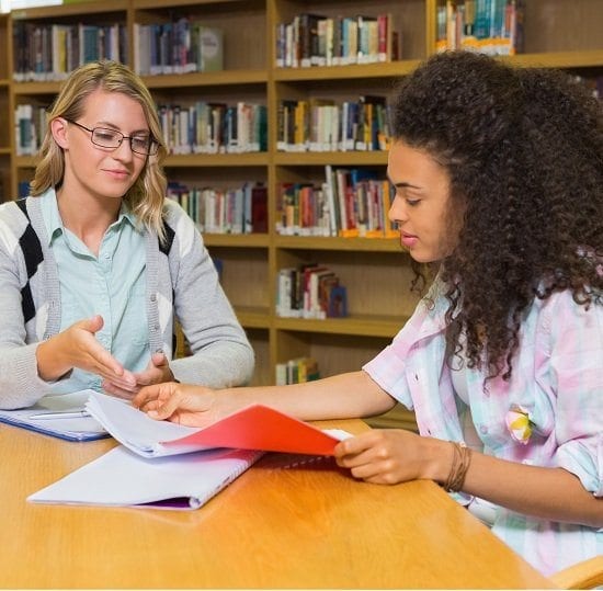 Older student helping a younger student with their studies.