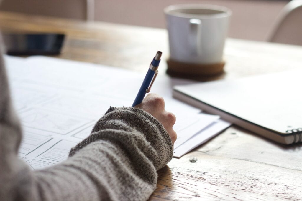 Student writing on paper at a desk